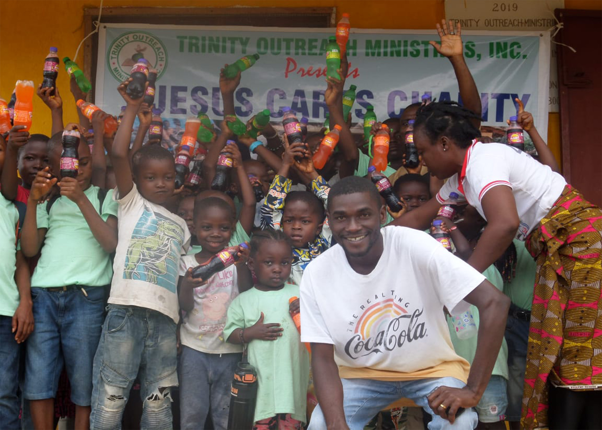 A group of boys in front of a Jesus Cares Charity banner, representing healthcare.
